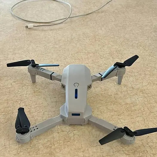 Quadcopter drone with four black propellers and blue status light
