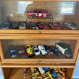 Diecast car collection in wooden display cabinet with multiple race cars