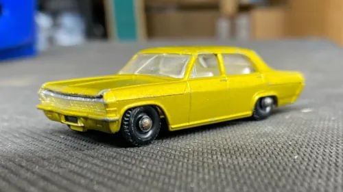 Yellow vintage diecast car model with chrome front bumper and black wheels