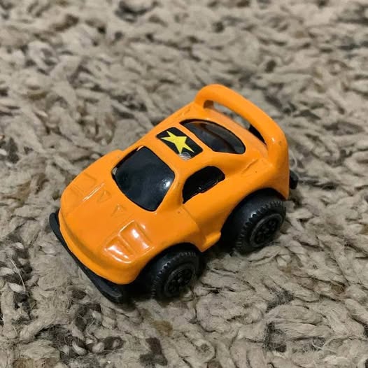 Orange small diecast car with black wheels, front three-quarter view.