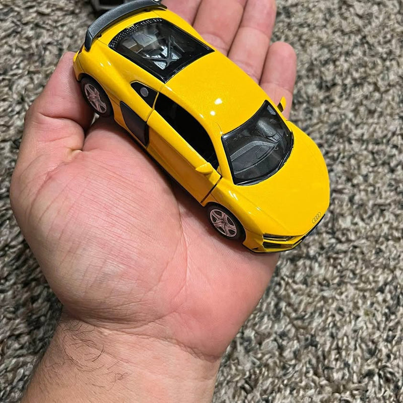 Yellow diecast sports car with black hood and grille, held in hand