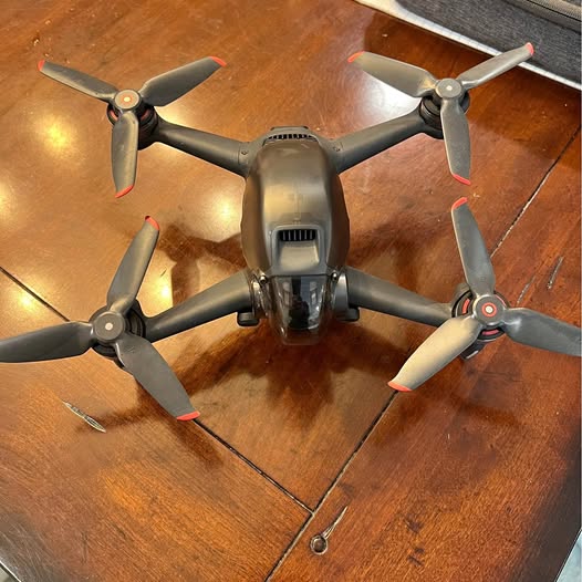 Quadcopter FPV drone with four gray propellers and central camera module, top view