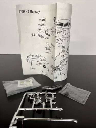 Diecast model kit sprues and parts with instruction sheet, grey metal pieces