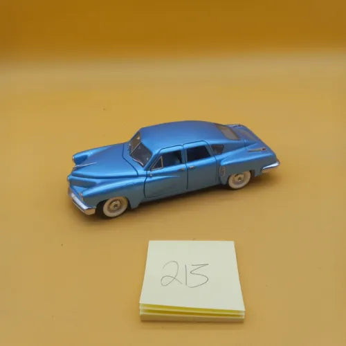 Blue 1:24 diecast model car with chrome grille and whitewall tires