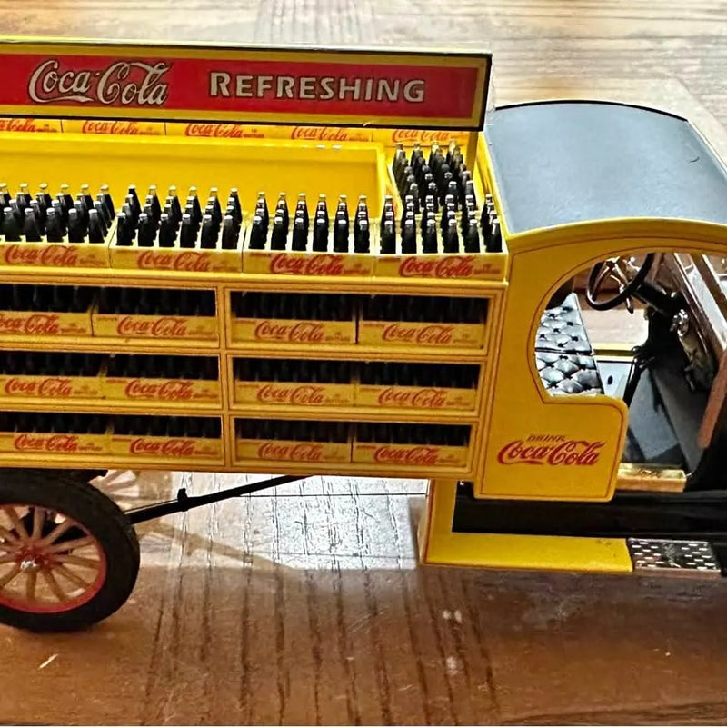 Yellow diecast Coca-Cola truck with red grille and printed signage, open cab detail