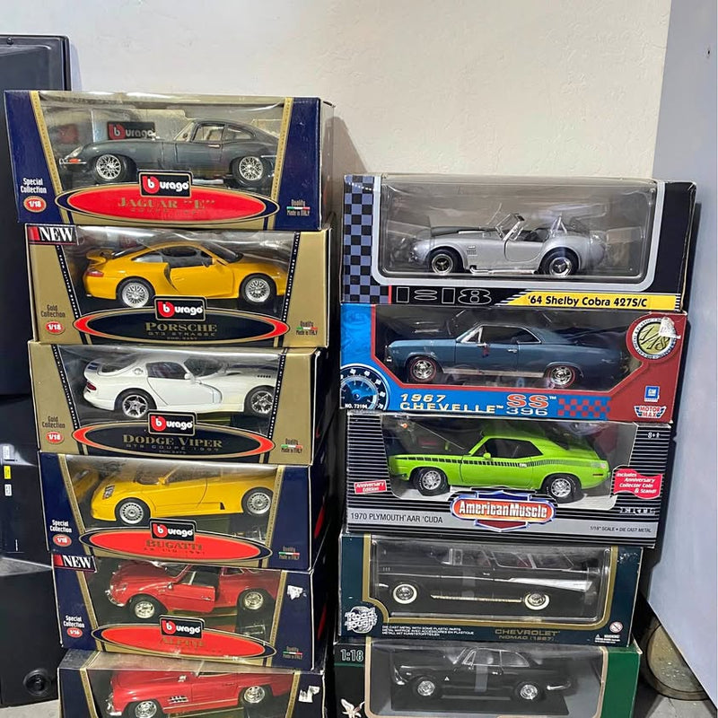 Diecast car lot with boxed model cars, including yellow Porsche and blue/red Chevelle
