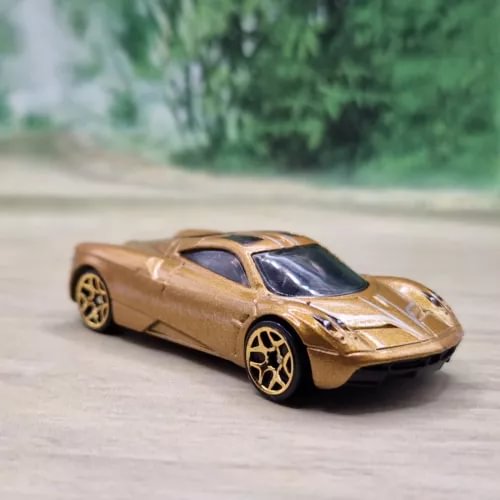 Gold diecast model car with black window area and black wheels, front quarter view.
