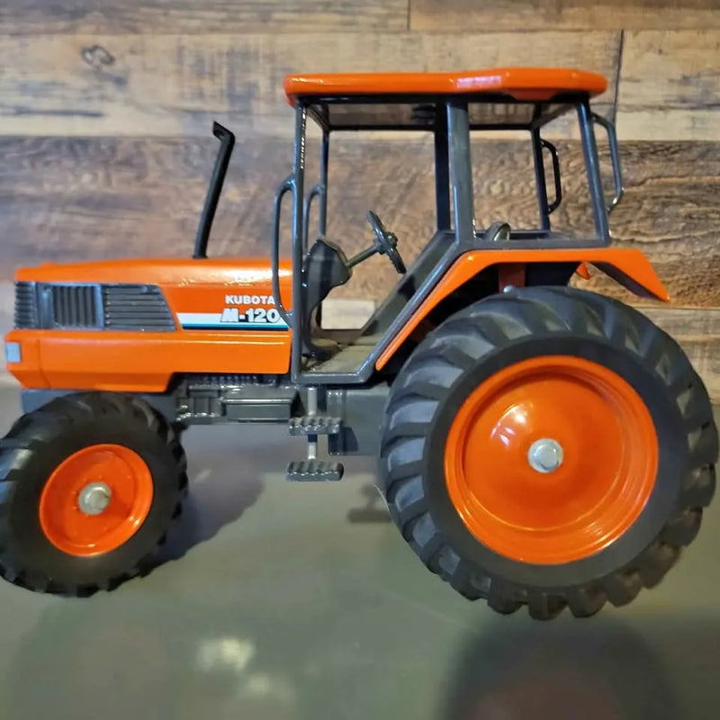 Diecast Kubota M120 tractor model, orange cab and black details, large treaded wheels