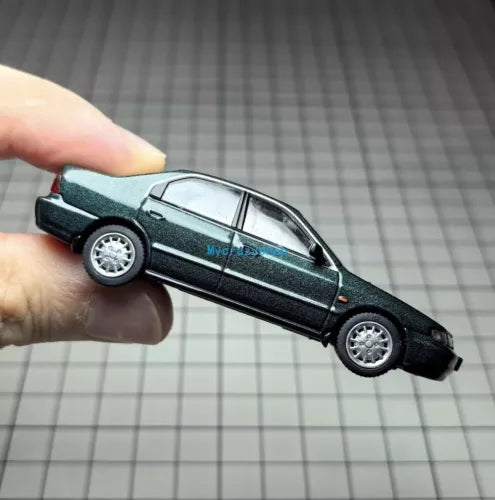 Dark green diecast sedan model car toy, side view with silver wheels
