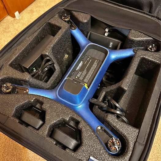 Blue drone in molded foam carrying case with accessories and tools