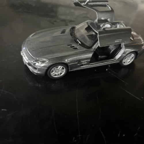 Grey diecast toy sports car model, front view with open driver door and silver wheels