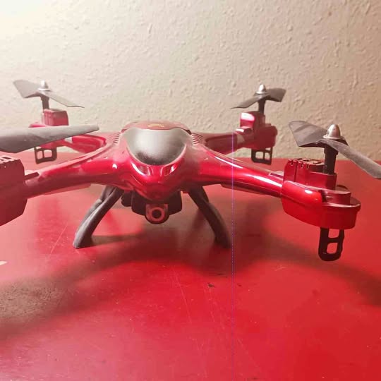 Red quadcopter drone with four propellers and front camera module