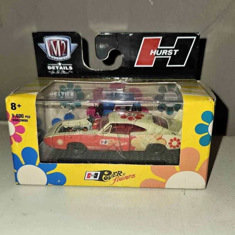 M2 diecast car in yellow floral display box, clear window showing red Hurst-style car