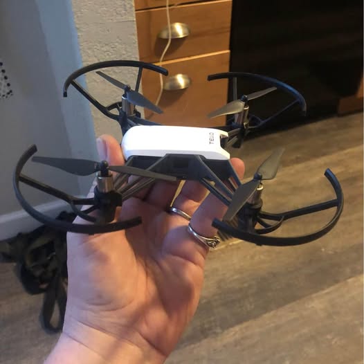 Small quadcopter drone with four propellers and dark frame, silver body