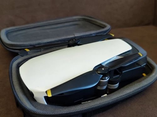 White quadcopter drone with propellers, stored in a zippered carrying case
