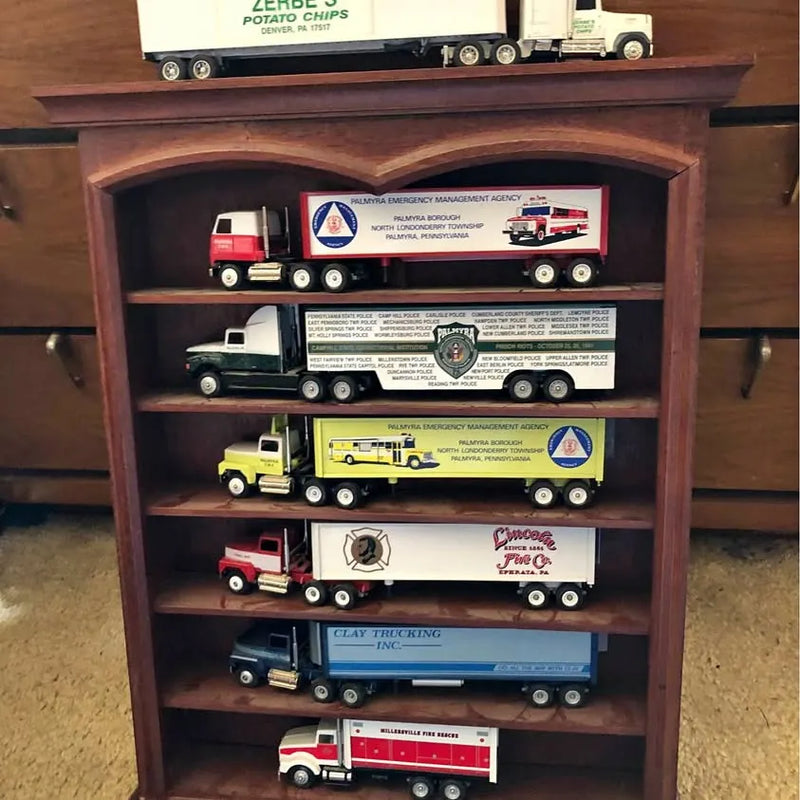 Diecast truck set with multiple colored trucks on wooden shelf