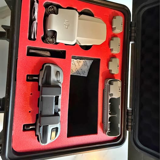 Hard case with gray drone body and accessories, including battery and remote parts