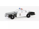 Police diecast sedan model car, white and black, front three-quarter view with light bar