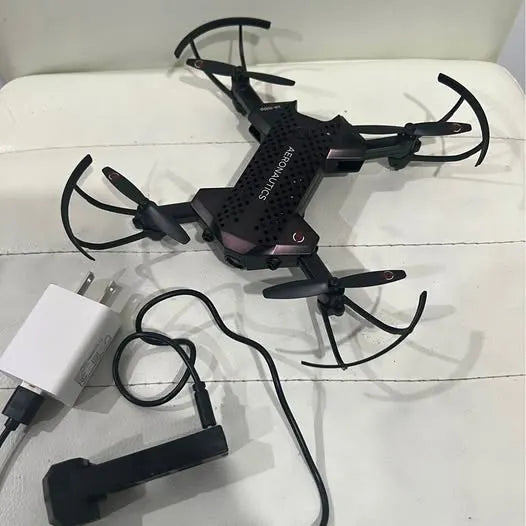Black quadcopter drone with four propeller guards, controller and charging cable