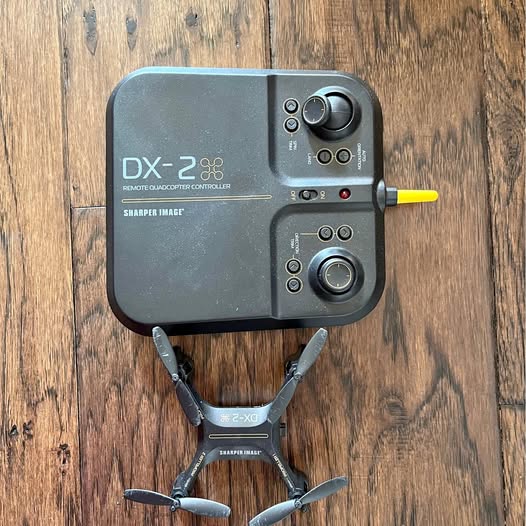 Black remote controller with two joysticks and compact stunt drone, top view