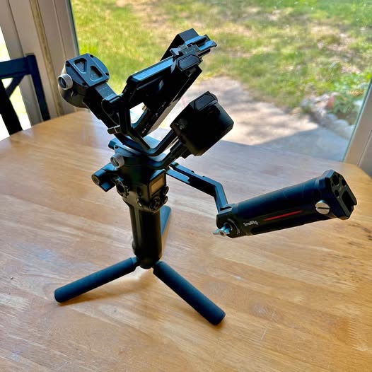 Folded DJI Ronin SC2 gimbal stabilizer with tripod legs, dark blue and black