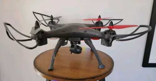 Grey quadcopter drone with red accents and bent prop guards, for parts
