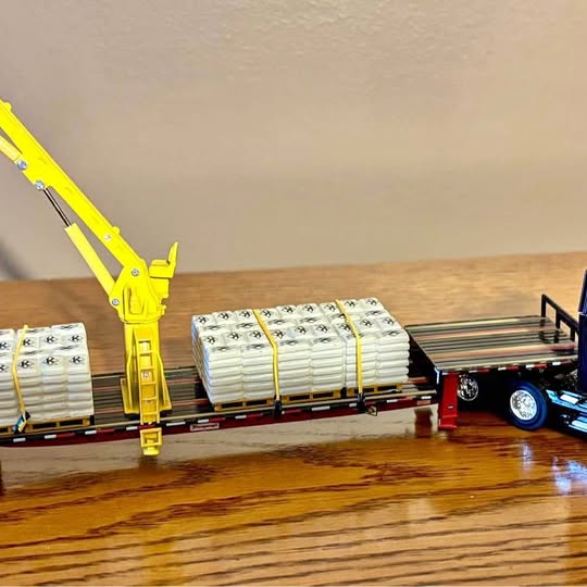 Diecast tractor-trailer truck with yellow pallet crane and white cargo pallets