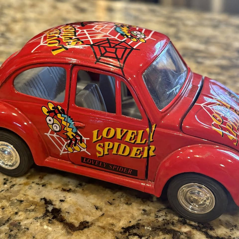 Red diecast VW Beetle toy car with spider decals and open windows