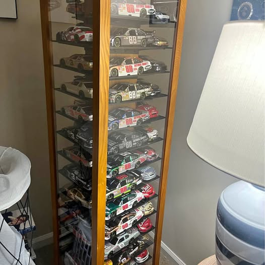 NASCAR diecast car display cabinet with assorted model cars behind glass