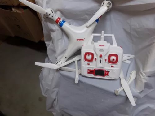 White quadcopter drone with four propellers and white remote controller transmitter