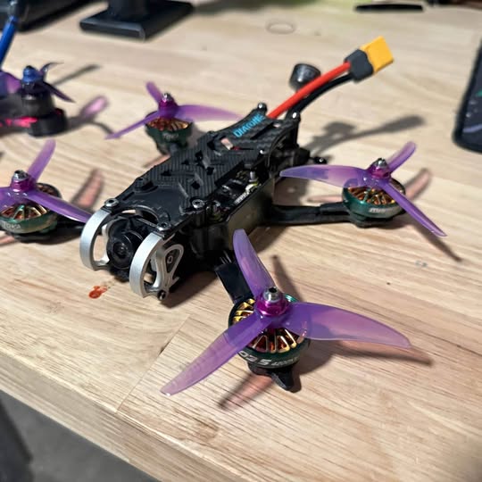 Black FPV racing drone with purple propellers and red battery lead