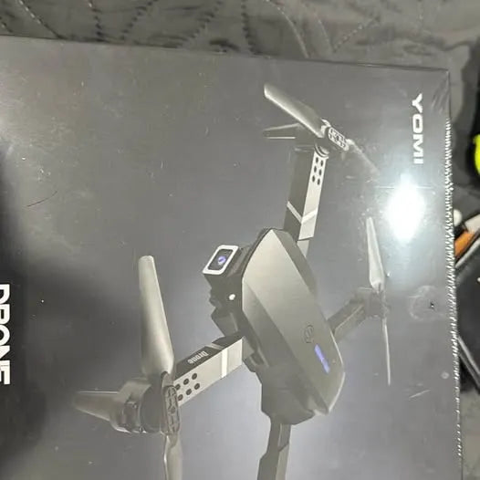 Foldable gray quadcopter drone with four propellers on retail box