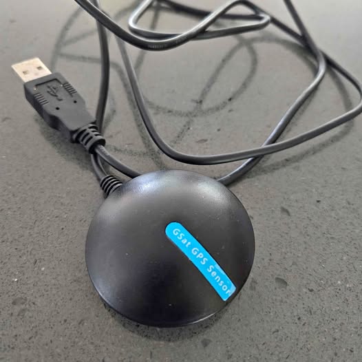GPS puck with blue sensor label and attached USB cable
