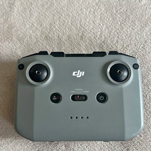 Light gray DJI drone controller with two joysticks and front circular grips