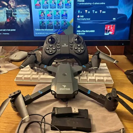 Quadcopter drone with four arms and central body, with controller nearby