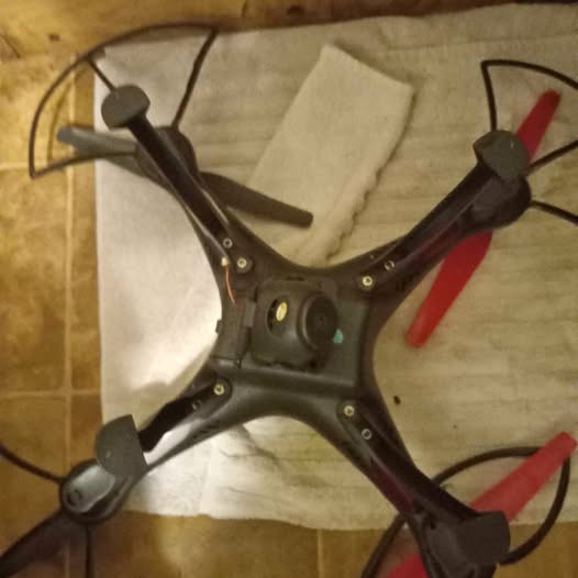 Black quadcopter drone with four propeller arms and central camera module