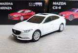 White diecast sedan model car, front three-quarter view with chrome grille and headlights