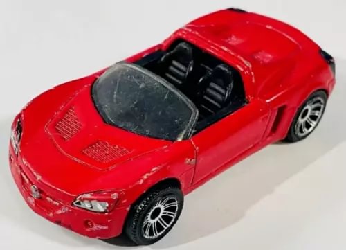 Red diecast toy car with black interior, front three-quarter side view