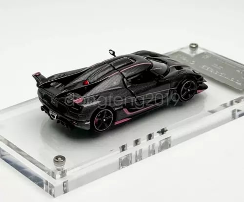 1:64 diecast racing sports car, black with pink accents, on clear display base