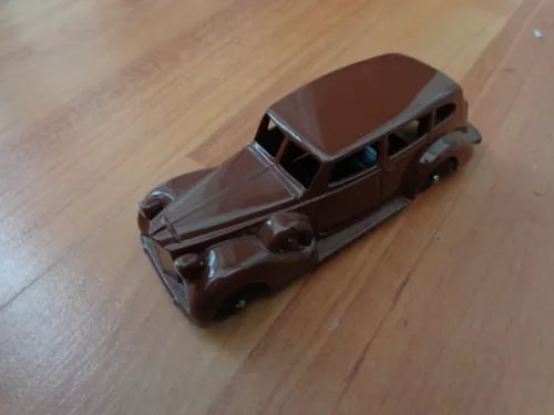 Diecast sedan model car in dark brown with chrome grille and headlights