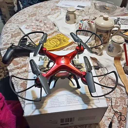 Red quadcopter drone with four propellers and front camera