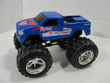Blue monster truck diecast toy with oversized black tires, front 3/4 view