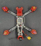 Orange 5-inch FPV drone with four propellers and wiring on frame