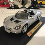 Silver diecast model car with black hood insets and dark windows on display base