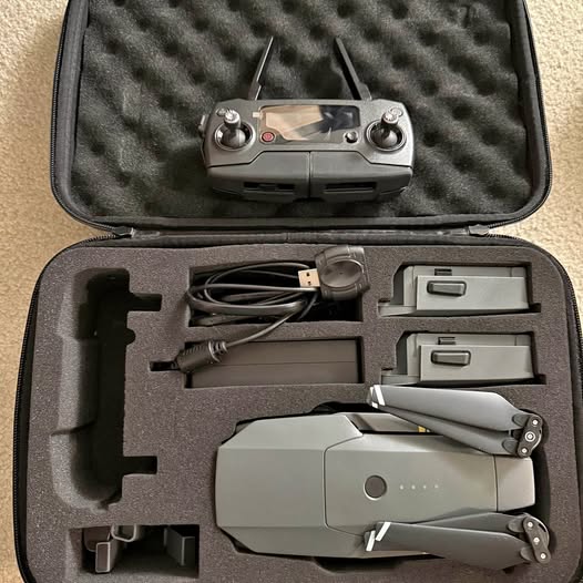 Grey quadcopter drone in foam-lined carrying case with remote and cables