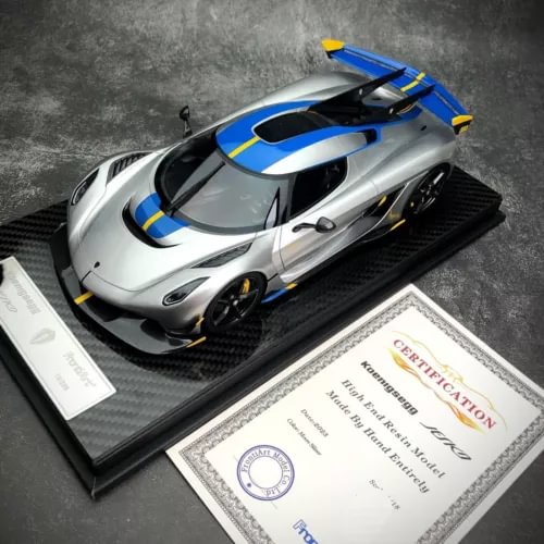 Resin diecast sports car model, silver with blue stripes, on display base