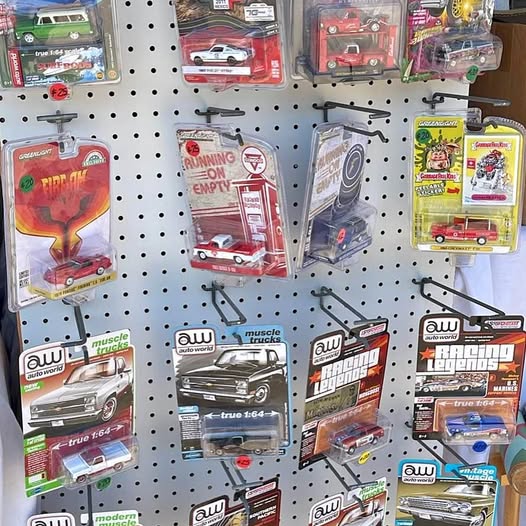 Assorted diecast car blister packs on a pegboard, various red and blue models