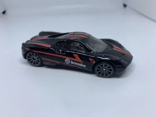 Black and red diecast race car model with Brembo logo, 1:64 scale, side view.
