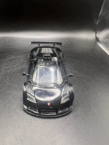 Diecast race car model in dark gray with front grille and headlights, front view