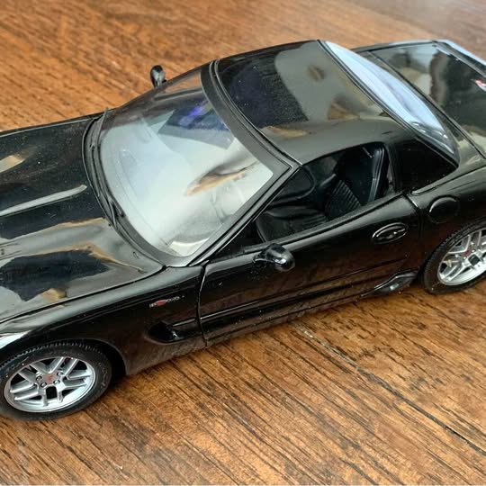 Black diecast sports car model with silver wheels, detailed front view